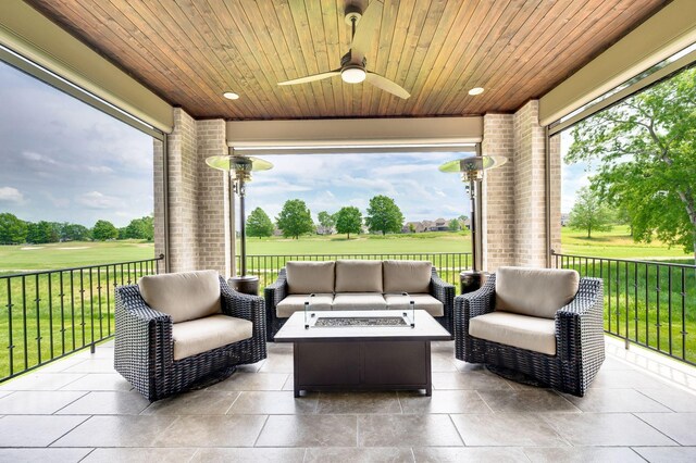 view of patio with ceiling fan, view of golf course, and an outdoor living space with a fire pit
