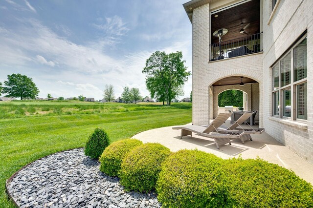 view of yard with a ceiling fan, a patio area, and a balcony