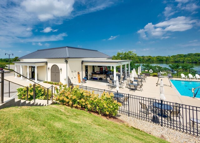 rear view of house featuring metal roof, a community pool, fence, a patio, and stucco siding