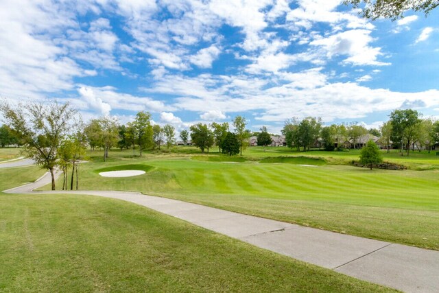 view of property's community with a lawn and view of golf course