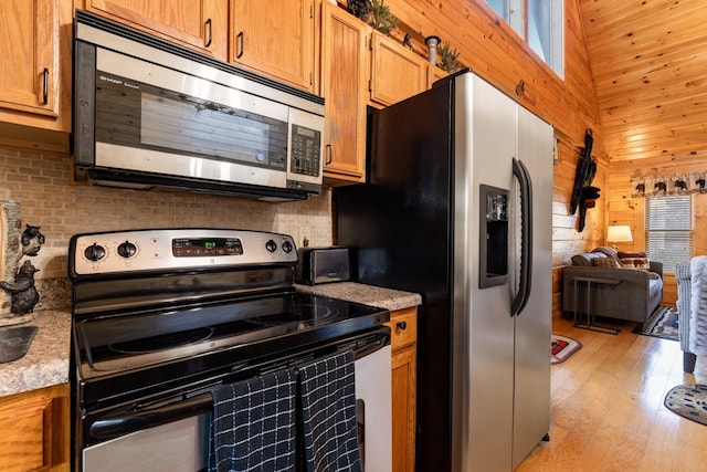 kitchen with light countertops, appliances with stainless steel finishes, light wood finished floors, and open floor plan