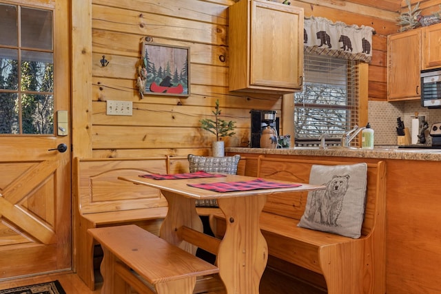 kitchen featuring backsplash, stainless steel microwave, and wood walls