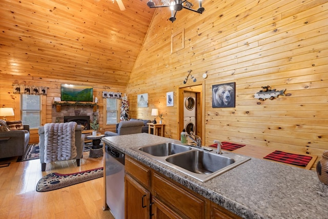 kitchen featuring stainless steel dishwasher, wooden walls, a sink, and stacked washer / dryer