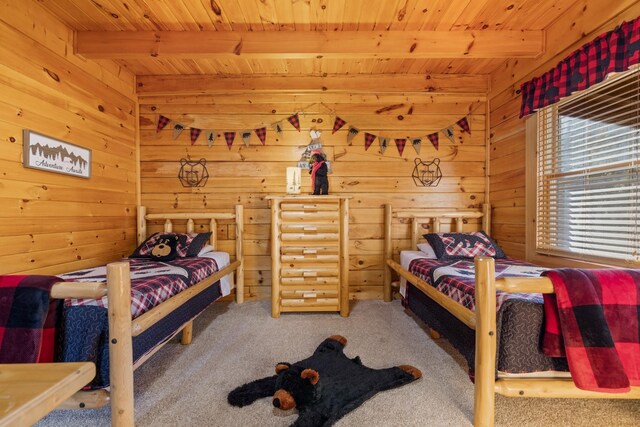 bedroom with wooden walls, wood ceiling, carpet flooring, and beam ceiling