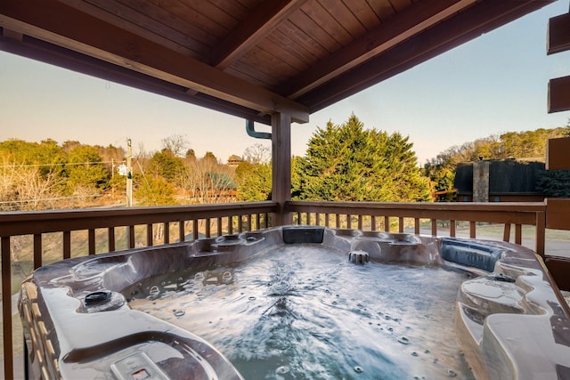 deck at dusk featuring a hot tub