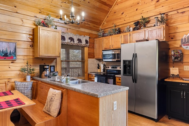 kitchen with a notable chandelier, a sink, stainless steel appliances, a peninsula, and vaulted ceiling