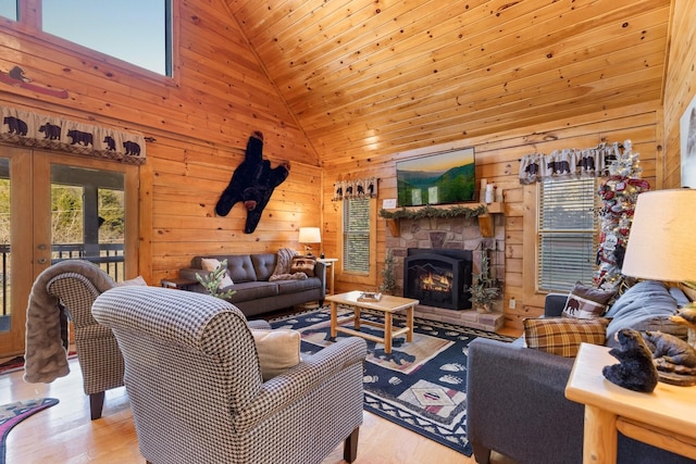 living room with a fireplace, wood finished floors, wooden walls, and high vaulted ceiling