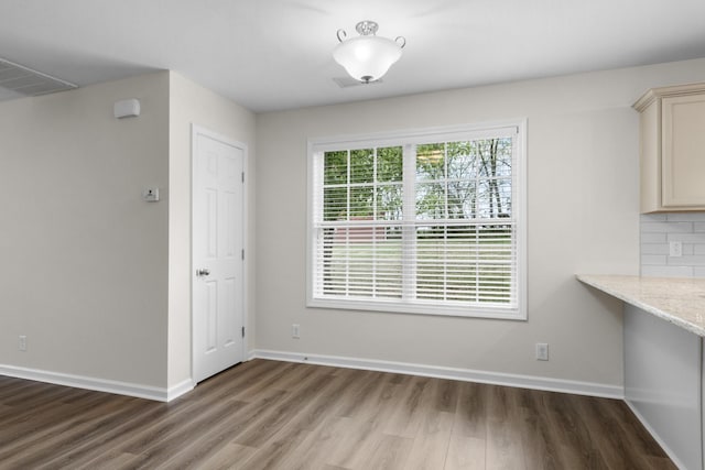 unfurnished dining area with baseboards, wood finished floors, and visible vents