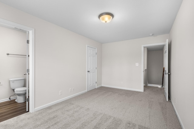 unfurnished bedroom with baseboards, carpet flooring, and connected bathroom
