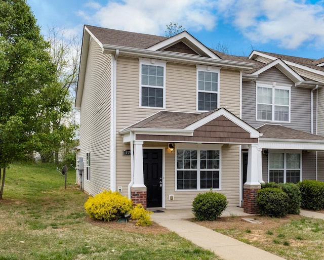 townhome / multi-family property with a shingled roof and a front lawn