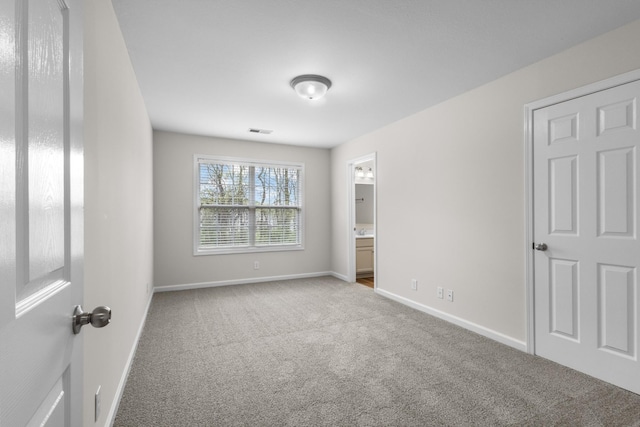 unfurnished bedroom featuring visible vents, carpet, ensuite bathroom, and baseboards