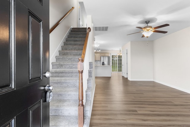 foyer entrance featuring ceiling fan, visible vents, wood finished floors, baseboards, and stairs