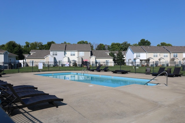 pool featuring a patio, a lawn, fence, and a residential view