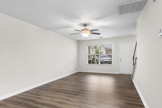 unfurnished room featuring stairs, a ceiling fan, visible vents, and dark wood-type flooring