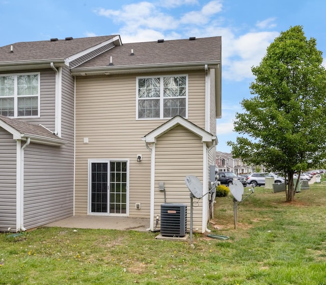 back of property featuring roof with shingles, a patio, a yard, and central AC