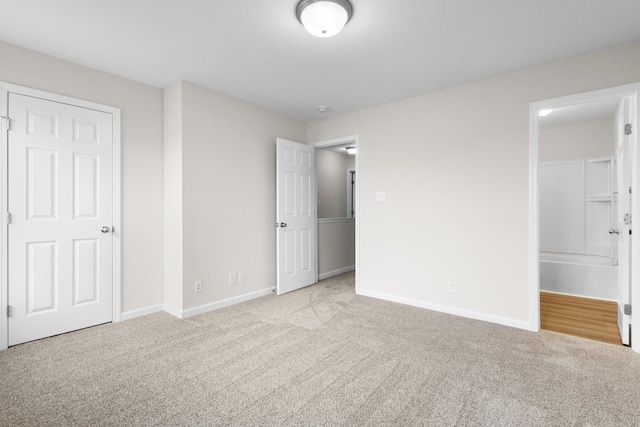 unfurnished bedroom featuring baseboards, carpet, and connected bathroom
