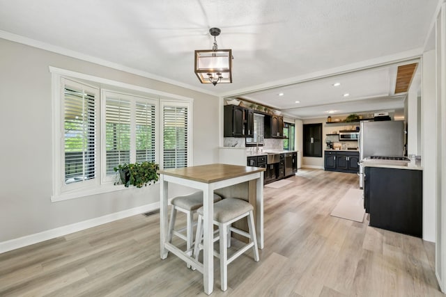 dining room featuring light wood-style floors, ornamental molding, and baseboards