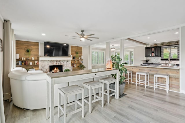 living room with light wood-type flooring, a ceiling fan, recessed lighting, and a fireplace