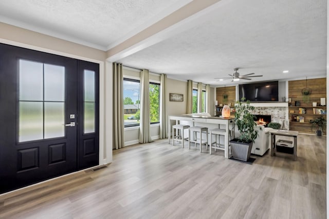 foyer entrance featuring a ceiling fan, a textured ceiling, a brick fireplace, and wood finished floors