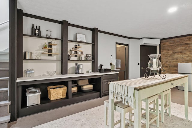 bar featuring crown molding, a wall unit AC, and freestanding refrigerator