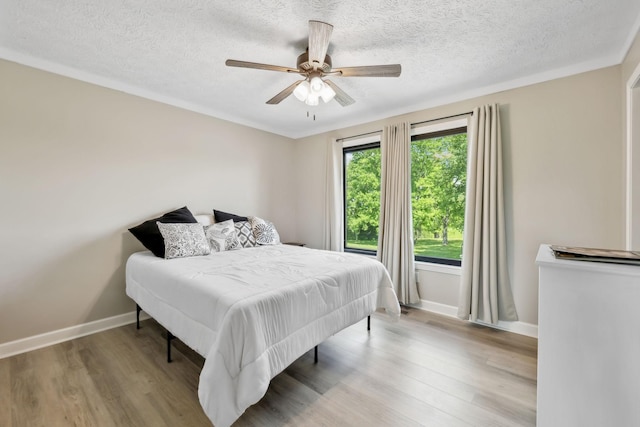 bedroom with baseboards, a textured ceiling, and wood finished floors