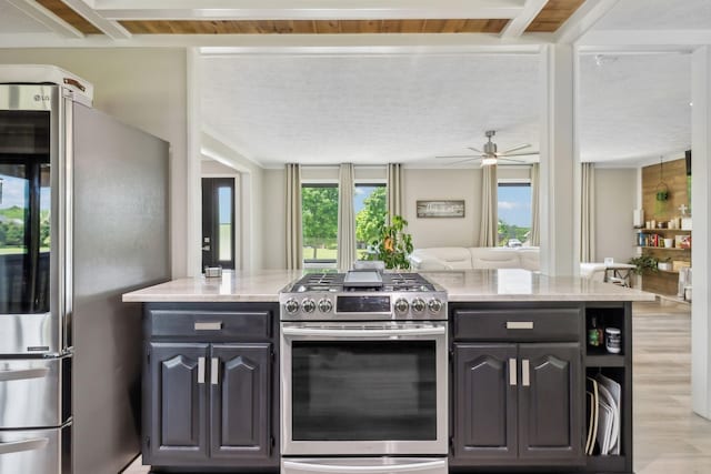 kitchen with ceiling fan, appliances with stainless steel finishes, light stone countertops, light wood finished floors, and open floor plan
