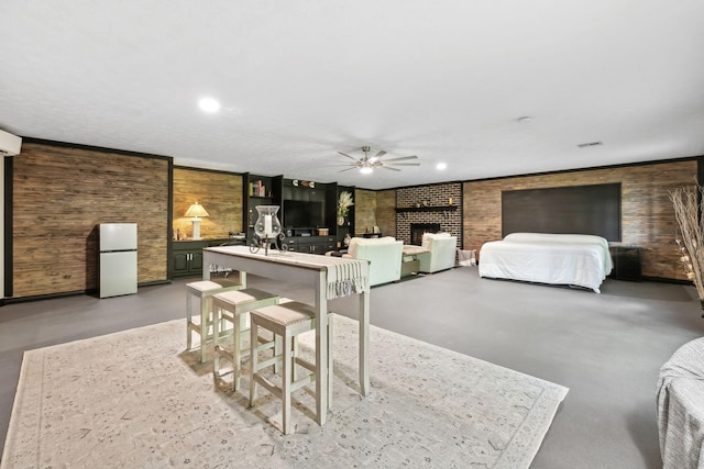 bedroom with wooden walls, concrete flooring, a brick fireplace, freestanding refrigerator, and visible vents