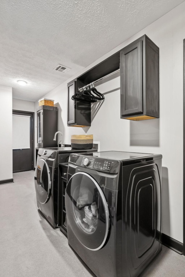 washroom with visible vents, baseboards, a textured ceiling, separate washer and dryer, and cabinet space