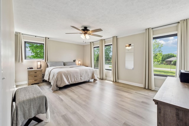 bedroom featuring baseboards, a ceiling fan, a textured ceiling, and light wood-type flooring