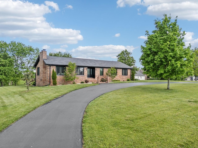 single story home with roof with shingles, a front lawn, aphalt driveway, brick siding, and a chimney