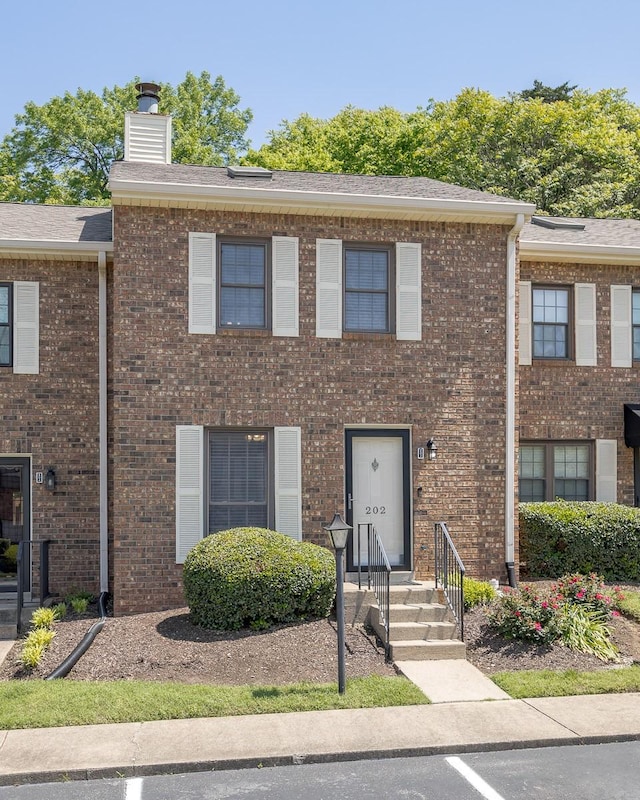 townhome / multi-family property with brick siding and a chimney