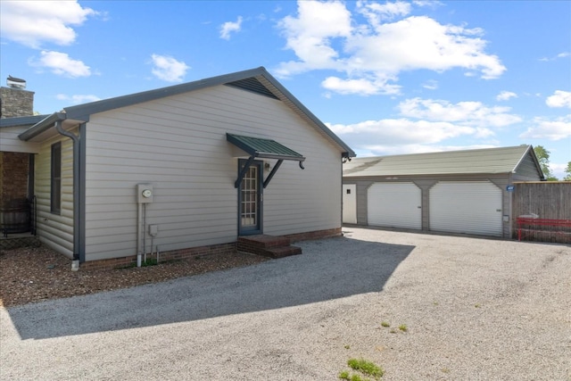 view of home's exterior with a garage, an outbuilding, and a chimney
