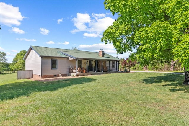 back of property with a lawn, a chimney, and metal roof