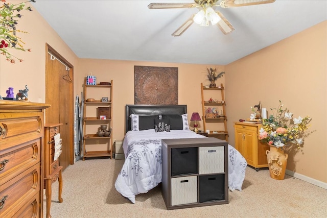 bedroom featuring light colored carpet, a ceiling fan, and baseboards