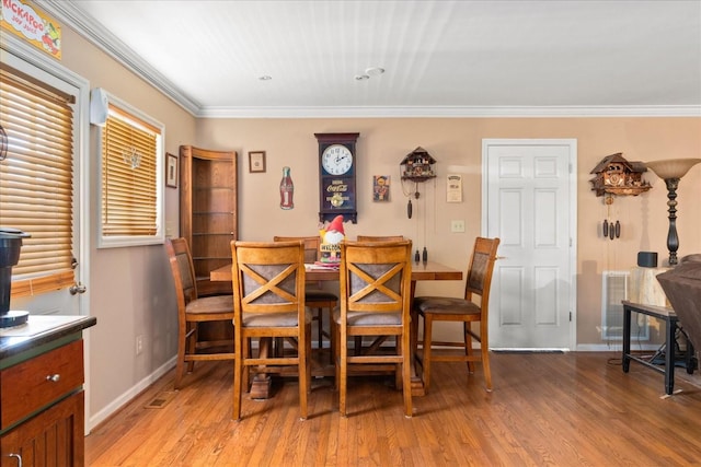 dining room featuring baseboards, light wood finished floors, and crown molding