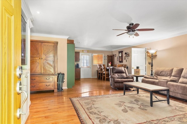 living area featuring crown molding, a ceiling fan, light wood finished floors, and baseboards