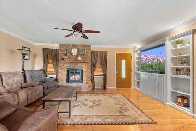 living area with crown molding, ceiling fan, a large fireplace, and wood finished floors