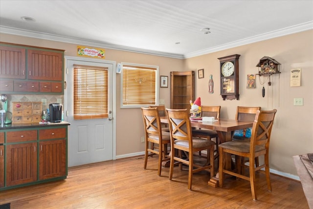 dining area featuring baseboards, ornamental molding, and light wood-style flooring