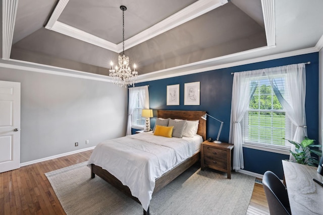 bedroom with an inviting chandelier, baseboards, a tray ceiling, ornamental molding, and hardwood / wood-style flooring