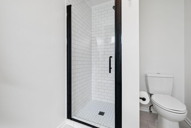 bathroom featuring baseboards, tile patterned floors, a stall shower, and toilet