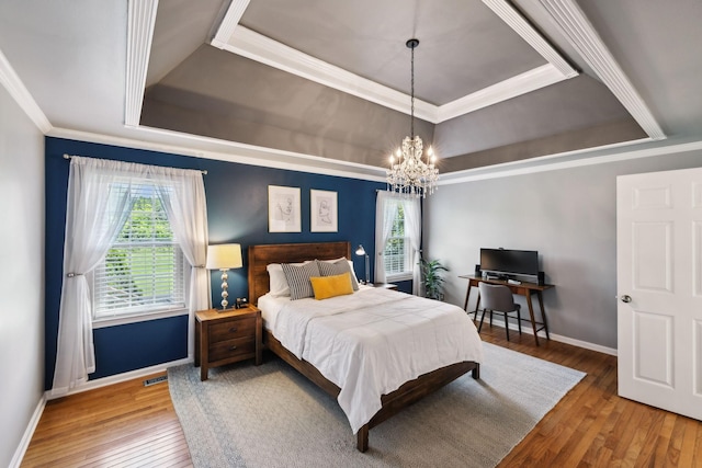 bedroom with a notable chandelier, baseboards, a tray ceiling, visible vents, and hardwood / wood-style flooring
