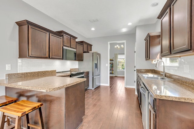 2095 Longhunter Chase Dr, Spring Hill, TN 37174 - kitchen featuring decorative backsplash, a peninsula, dark brown cabinets, a sink, and stainless steel appliances