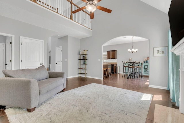 2095 Longhunter Chase Dr, Spring Hill, TN 37174 - living room featuring a towering ceiling, baseboards, dark wood-style floors, arched walkways, and ceiling fan with notable chandelier