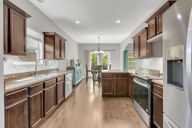 2095 Longhunter Chase Dr, Spring Hill, TN 37174 - kitchen with an inviting chandelier, a sink, light wood-style floors, stainless steel appliances, and a peninsula
