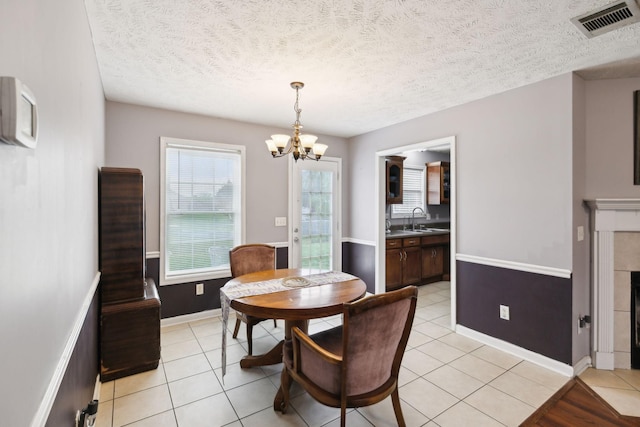 dining area featuring light tile patterned floors, a textured ceiling, visible vents, and an inviting chandelier
