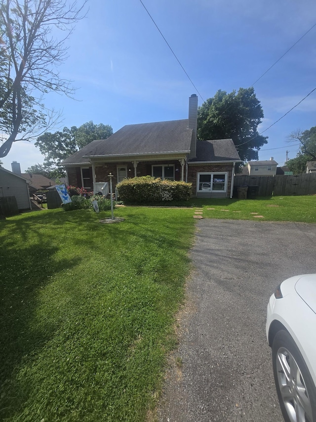 view of front of home with a front lawn, fence, and a chimney