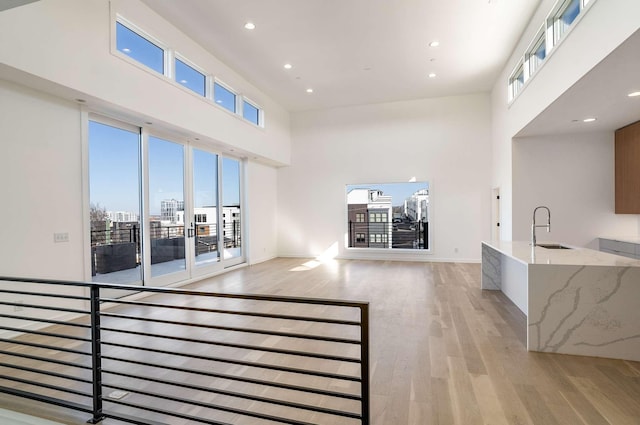 1017 12th Ave S Unit A, Nashville, TN 37203 - unfurnished living room with a sink, baseboards, a high ceiling, recessed lighting, and light wood-style flooring