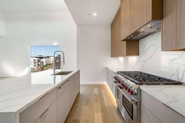 1017 12th Ave S Unit A, Nashville, TN 37203 - kitchen featuring decorative backsplash, range with two ovens, light stone countertops, a sink, and light wood-style floors