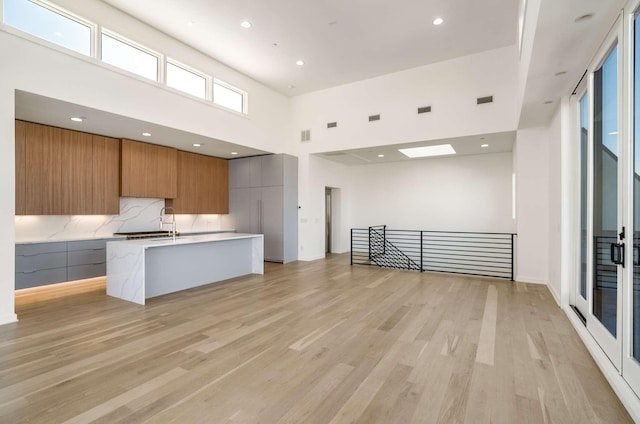 1017 12th Ave S Unit A, Nashville, TN 37203 - kitchen with a high ceiling, open floor plan, light wood-type flooring, a center island with sink, and modern cabinets