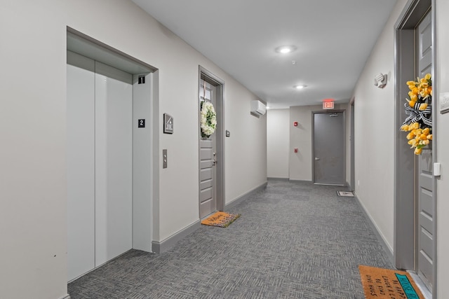 hall with carpet flooring, elevator, a wall unit AC, and baseboards